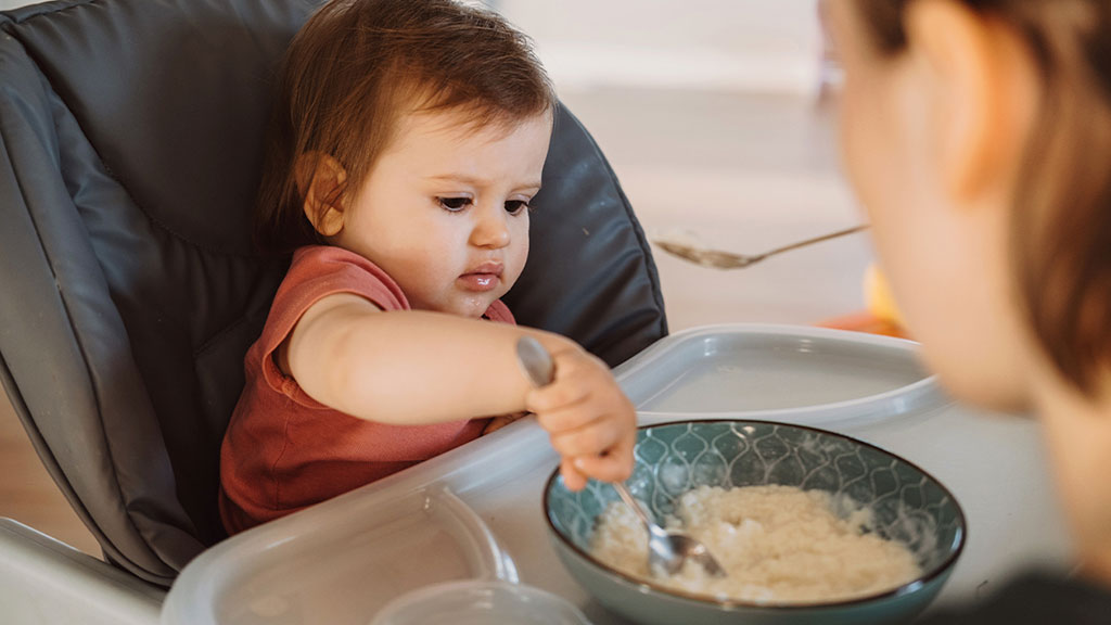 Niño lactante (7-8 meses) tomando preparado de cereales o papilla de cereales. 