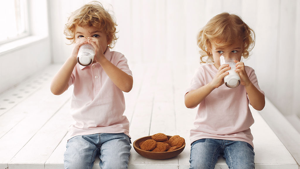 Niños/niñas de 2-3 años bebiendo un vaso de leche.